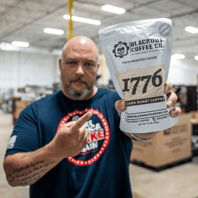1776 dark roast man holding the coffee bags