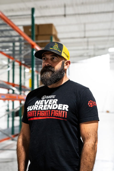 Man wearing a black t-shirt with 'Never Surrender Fight Fight Fight' text in a warehouse setting.