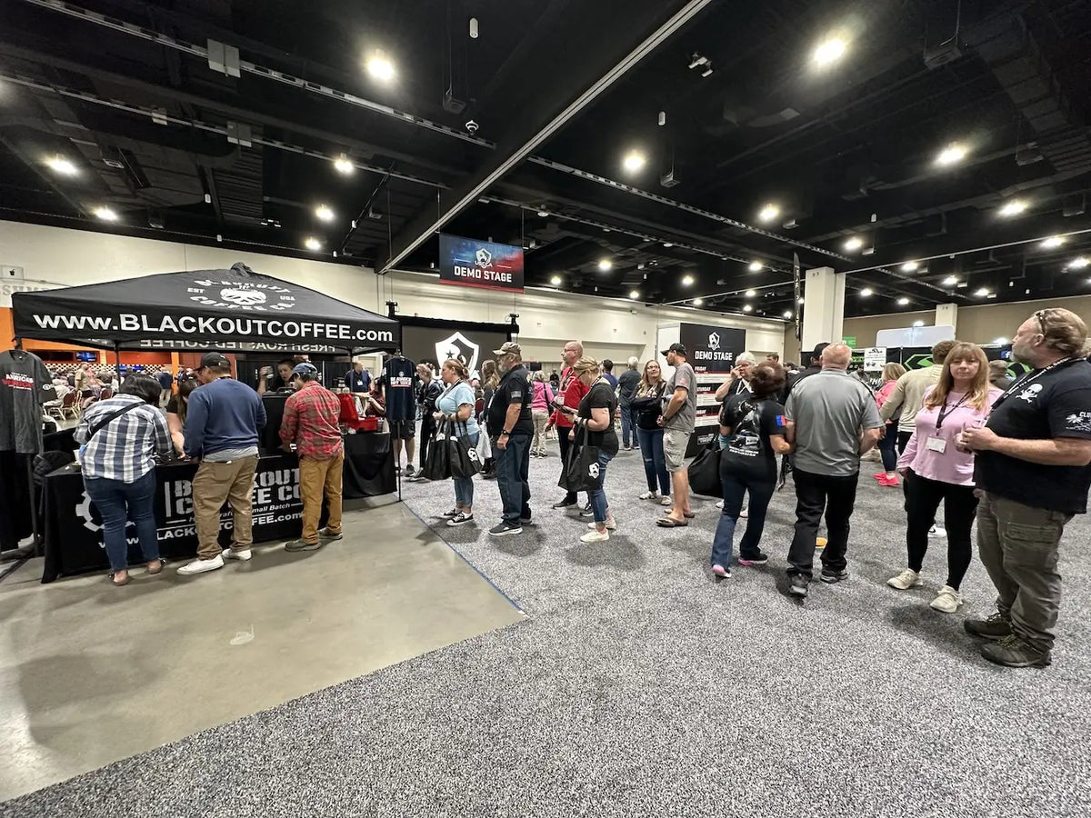 Visitors gathering around the Blackout Coffee booth at a USCCA event