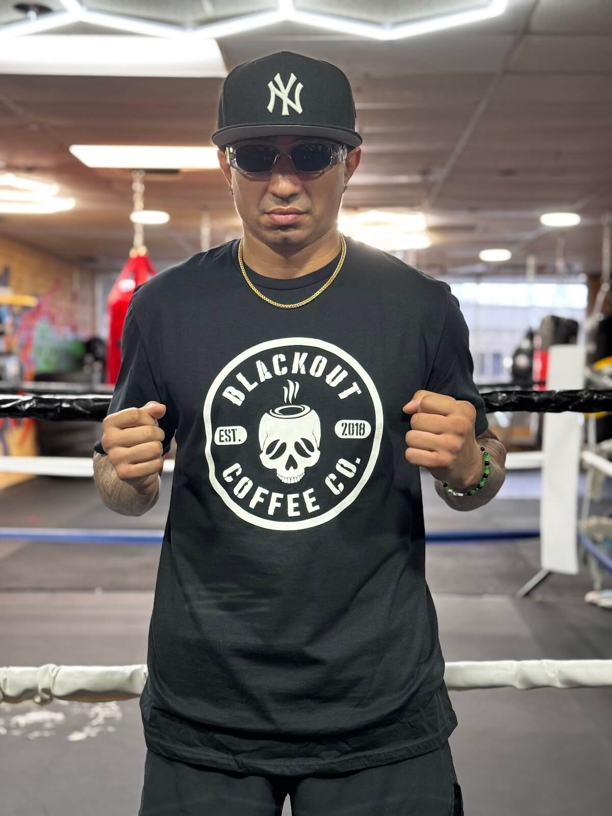 Person wearing a black t-shirt with 'Blackout Coffee Co.' logo in a gym setting