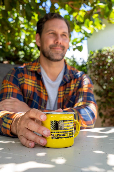 Man holding a yellow mug with an American flag design outdoors