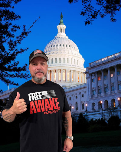 Jared Yanis wearing a black t-shirt with text in front of the U.S. Capitol building