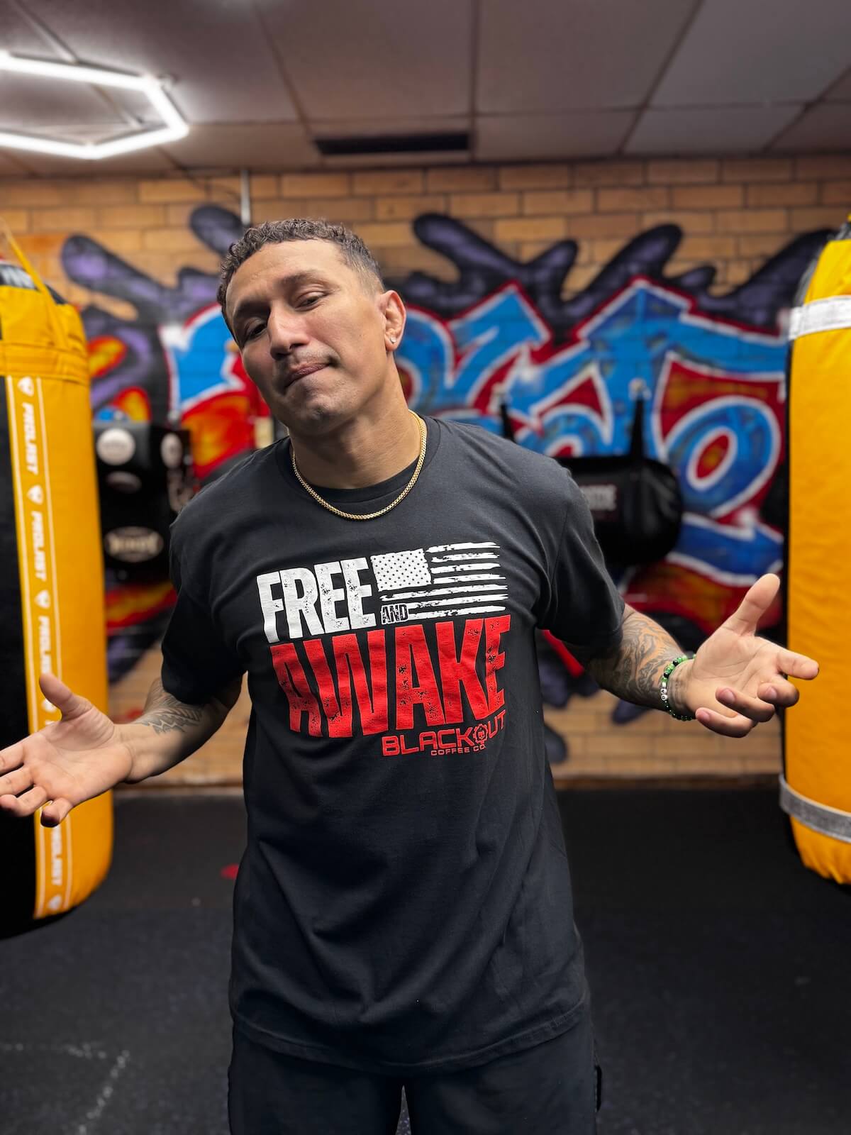 Tony Loco Soto wearing a black t-shirt with red and white text in a gym setting
