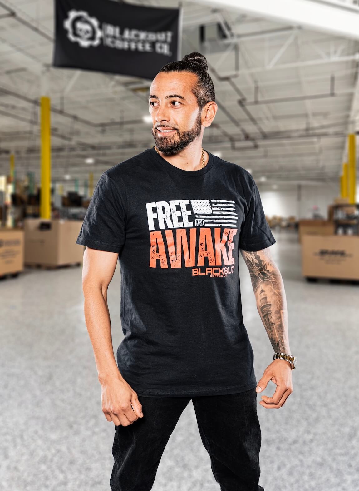 Man wearing a black t-shirt with 'Free Awake' text in a warehouse setting