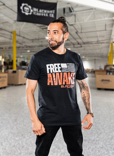 Man wearing a black t-shirt with 'Free Awake' text in a warehouse setting
