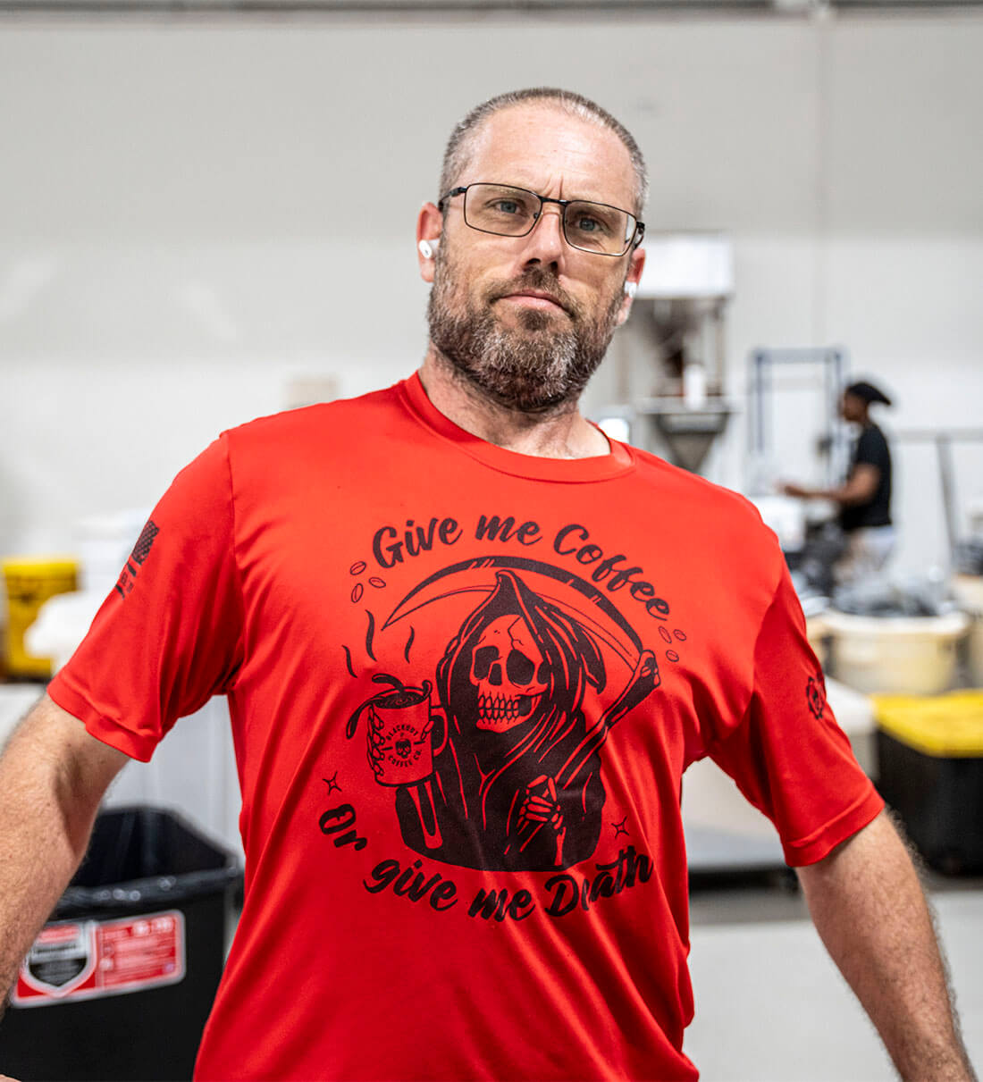 Man wearing a red t-shirt with a graphic design and text in a casual setting.