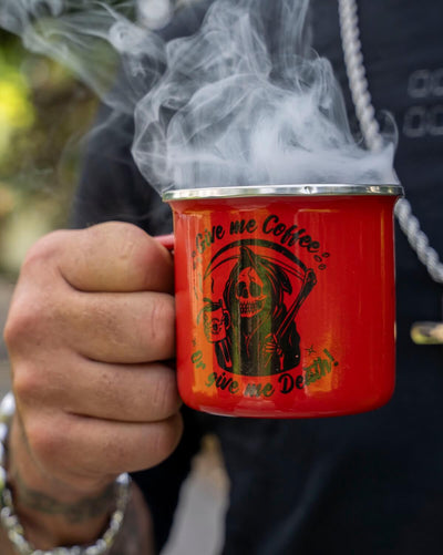Red mug with a coffee-themed design held by a person, surrounded by smoke.