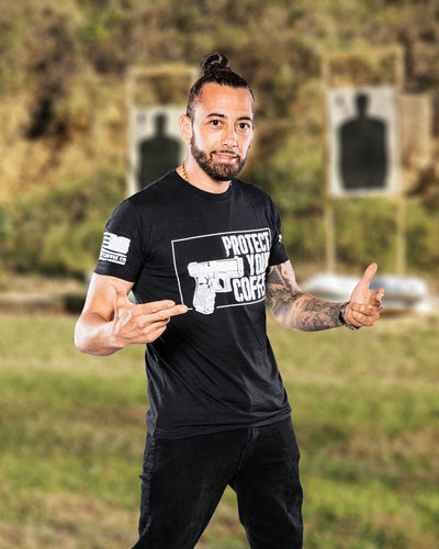 Man wearing a black t-shirt with a graphic design, standing outdoors with a blurred background.