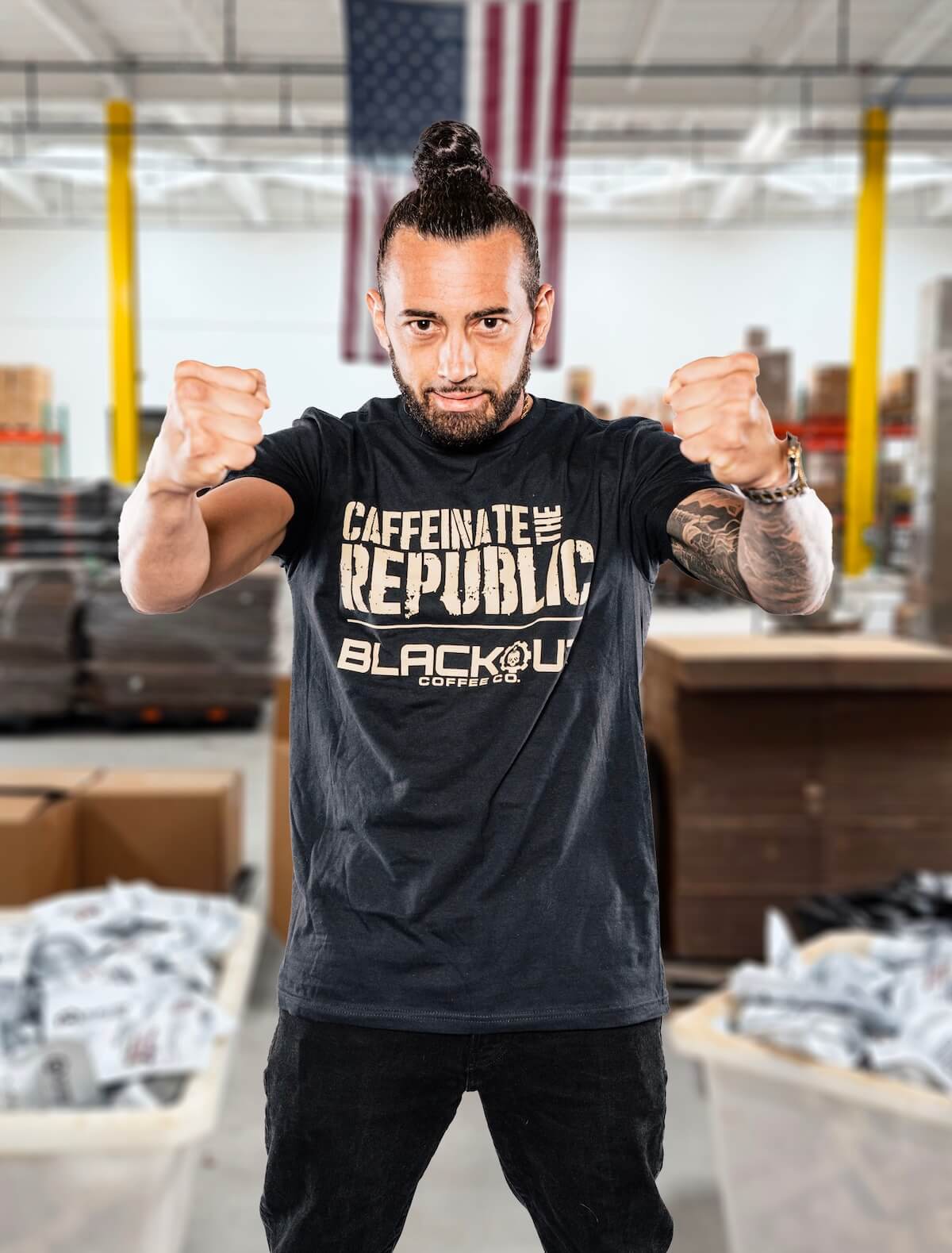 Person wearing a 'Caffeinate the Republic Blackout' t-shirt in a warehouse setting