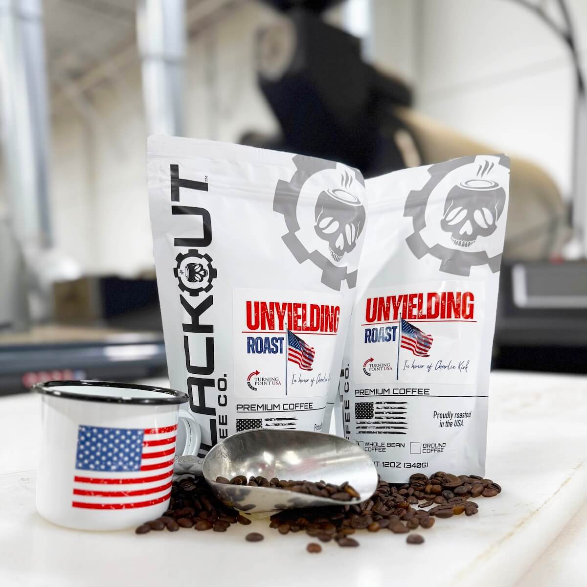 Two bags of 'Unyielding Roast' coffee with a mug in front of roaster.
